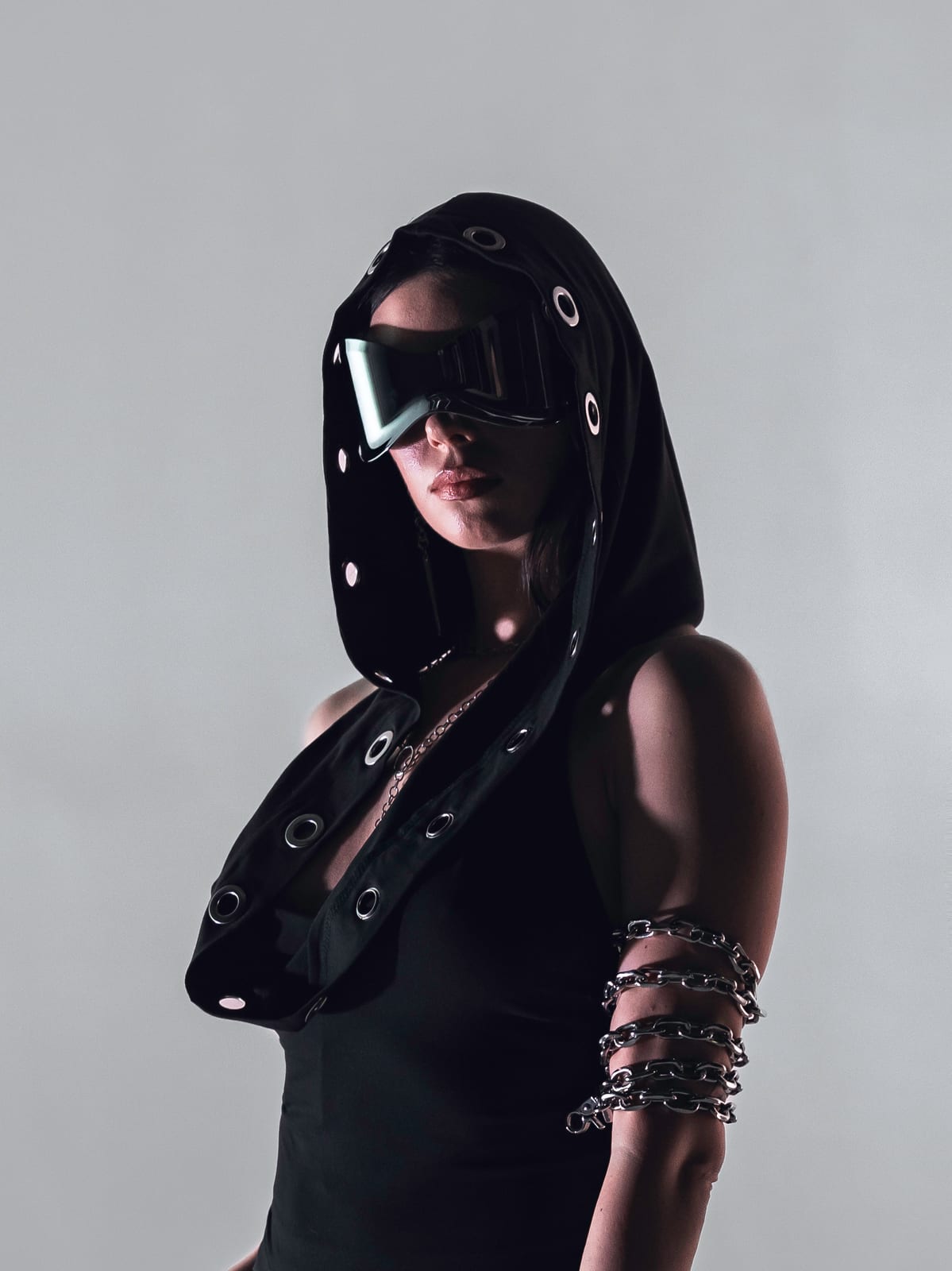 ELL3NI in hooded mask and goggles, standing studio portrait
